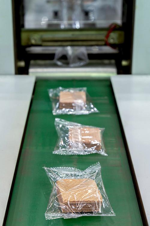 饼干的包装在塑料背面在生产线上的自动包装机的输送带在面包房工厂